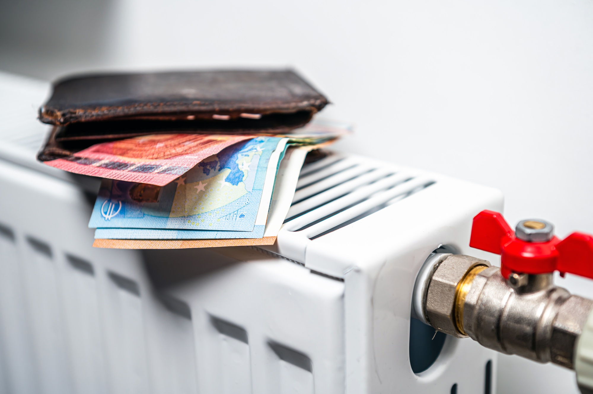 wallet with euro banknotes on central heating radiator, concept of expensive heating costs, closeup